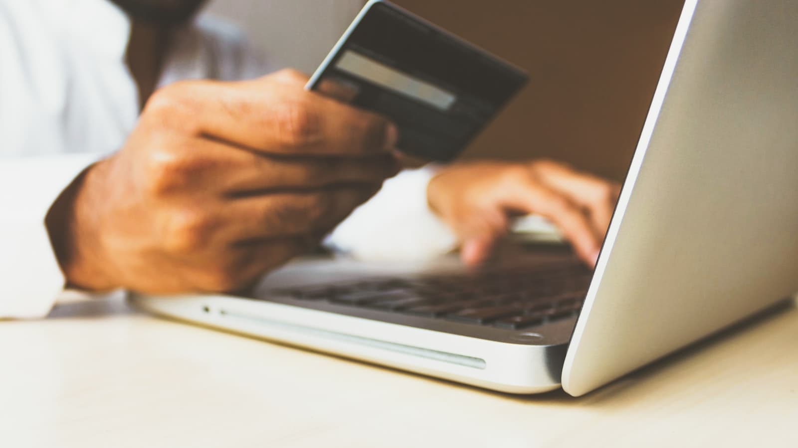 Hands entering credit card details into a laptop for an online purchase